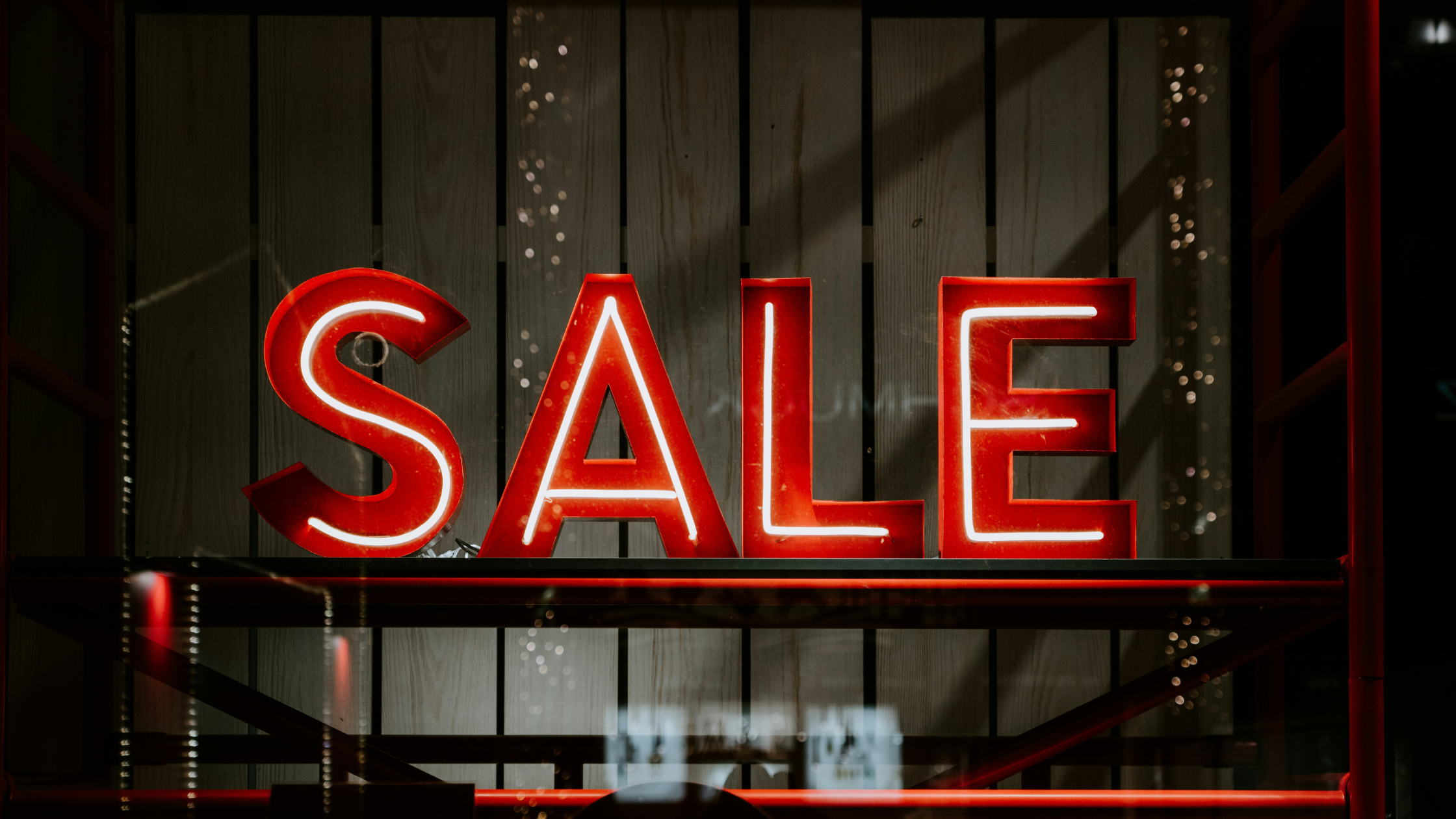 Bright red SALE neon sign highlighting top selling products in the store window display