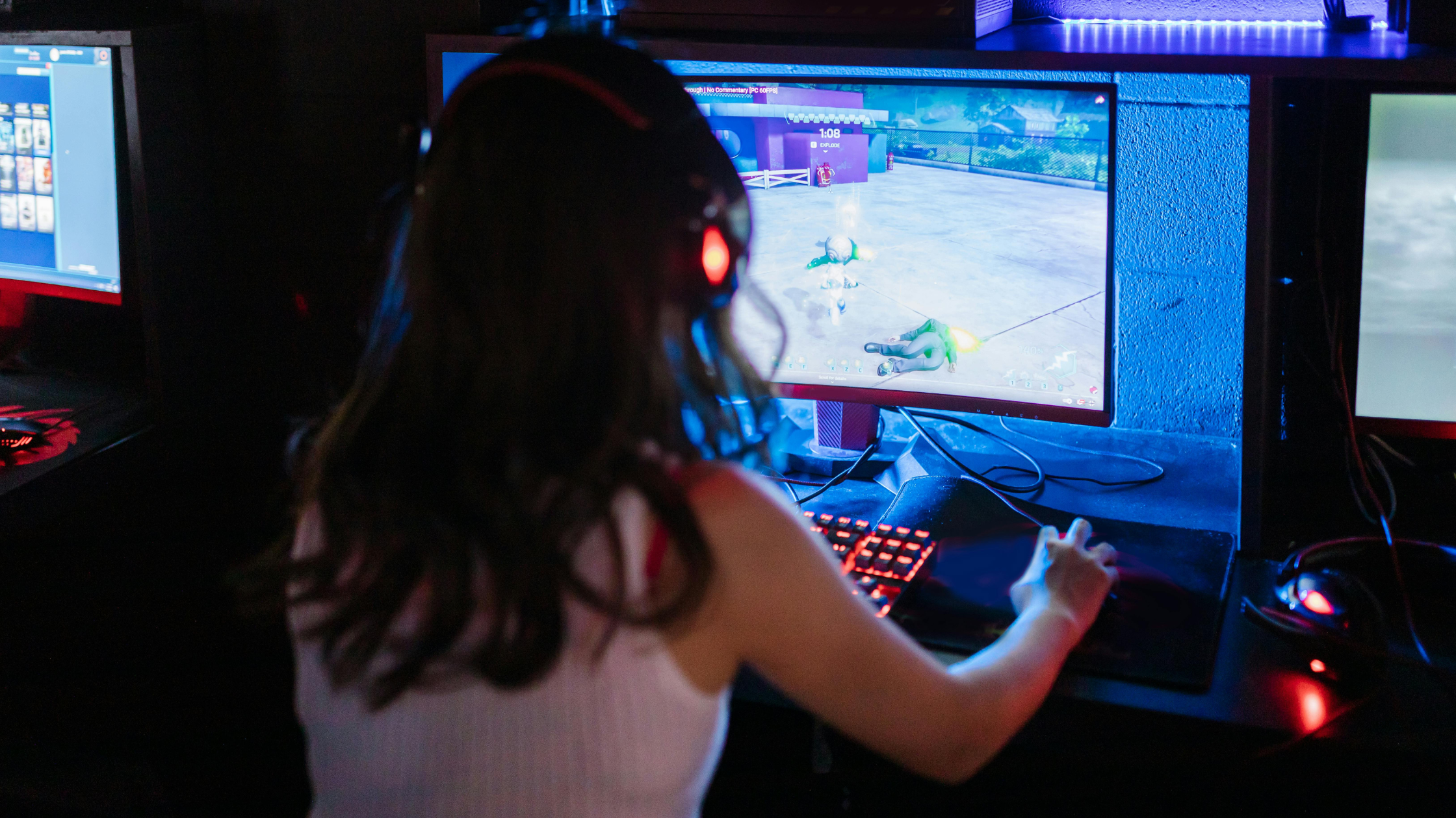 Gamer using affordable gaming mouses with glowing keyboard playing video games on a desktop setup