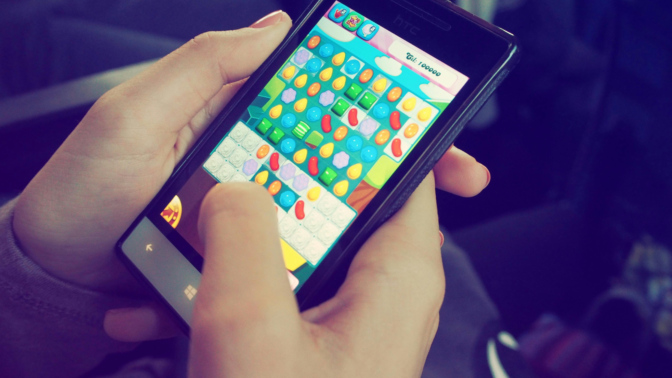 Person playing a colorful puzzle game on a smartphone showcasing mobile gaming accessories