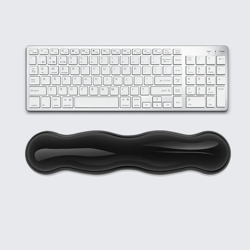 HandsCross ergonomic keyboard wrist rest in black placed below a white wireless keyboard for comfortable typing support